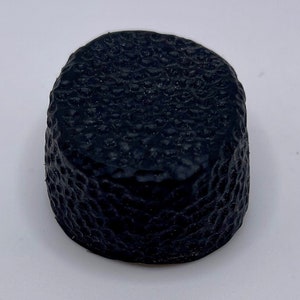 May include: A black rubber puck with a textured surface.
