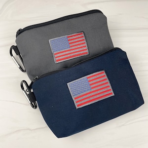 May include: Two small zippered pouches with American flag patches. The top pouch is gray and the bottom pouch is navy blue.