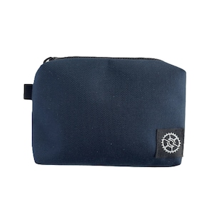 K&ouml;nnte beinhalten: Eine dunkelblaue Rei&szlig;verschlusstasche mit einem kleinen schwarzen Patch mit einem silbernen Zahnradlogo.