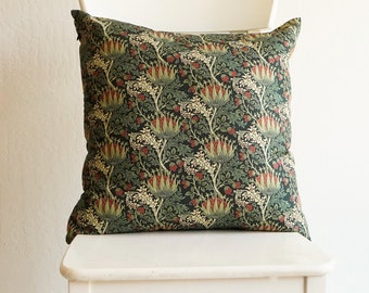 May include: A green, red, and white floral patterned throw pillow on a white chair.