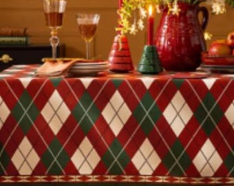 Peut inclure: Nappe de table à carreaux rouges, verts et blancs avec un motif en losanges. La nappe a une bordure avec un motif répété de petits triangles verts et blancs.