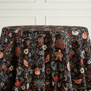 May include: A round tablecloth with a dark background and a detailed floral and bird pattern. The design features red, white, and green elements, creating a classic and elegant look. The tablecloth is suitable for dining or decorative purposes.