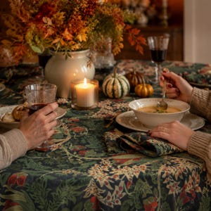Scottish Thistle tablecloth featuring a detailed botanical pattern of cream-colored thistle flowers, muted green foliage, and rust-red accents on a deep navy background. Styled on a dining table for a cozy autumn dinner, with seasonal pumpkins, warm candlelight, and coordinating table linens, creating an elegant vintage-inspired fall tablescape.
