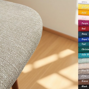 May include: A close-up of a light beige textured fabric, possibly upholstery. A colour chart on the right displays various fabric colours, including white, yellow, gold, pink, purple, red, navy, and black.