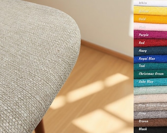 Puede incluir: Primer plano de una tela beige claro texturizada, posiblemente tapicería. Una carta de colores a la derecha muestra varios colores de tela, incluyendo blanco, amarillo, oro, rosa, morado, rojo, azul marino y negro.