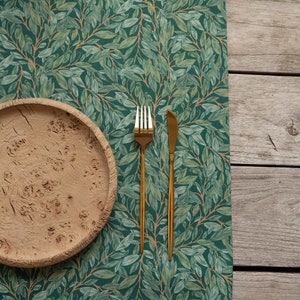 May include: A wooden plate with a rustic finish sits on a green and brown patterned tablecloth. A gold fork and knife are placed to the right of the plate.