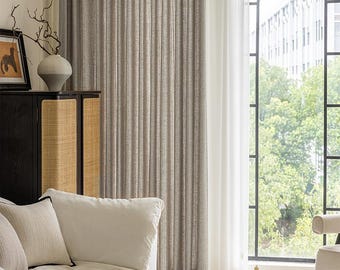 May include: A living room scene featuring a white sofa with decorative pillows, a marble-topped coffee table, and a black cabinet with woven panels. The room has neutral-toned curtains and a large arched window.
