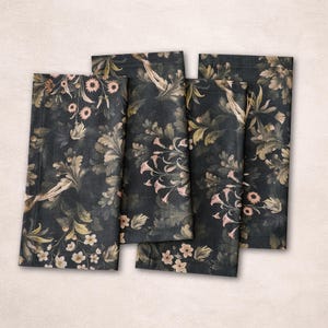 May include: Four dark napkins with a floral pattern. The napkins feature a dark background with a design of pink, beige, and green flowers and foliage. The napkins are rectangular and appear to be made of fabric.