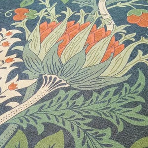 Könnte beinhalten: Nahaufnahme eines floralen Musters mit großen, stilisierten Blüten in Orange-, Grün- und Blautönen. Das Design umfasst detaillierte Blätter und Stiele und erzeugt eine strukturierte, botanische Ästhetik. Der Hintergrund ist dunkelblau.
