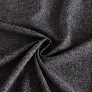 May include: A dark charcoal gray fabric with a visible woven texture and a subtle heathered appearance. The material is gathered in the center, creating deep, flowing folds and shadows that highlight the dense, interlaced weave of the textile.