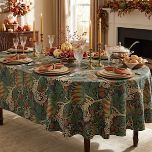 May include: A dark green tablecloth with a repeating botanical pattern of red berries and foliage. The table is set with white plates, orange cloth napkins, clear glassware, brass candlesticks, and a centerpiece bowl filled with autumn fruits.