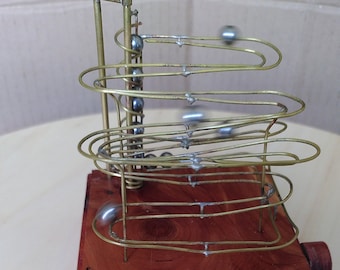 Marble Machine, rolling ball sculpture made of brass wire with steel balls and a larch wood base