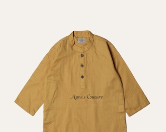 Puede incluir: Un conjunto de dos piezas para un niño, que consta de una camisa de manga larga de color amarillo mostaza con cuello abotonado y el texto "Ayra's Couture" bordado en la parte delantera, y pantalones blancos.