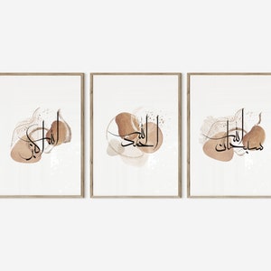 May include: Set of three framed prints with Arabic calligraphy in black on a white background. Each print features a different phrase in Arabic script, surrounded by abstract brown watercolor shapes.