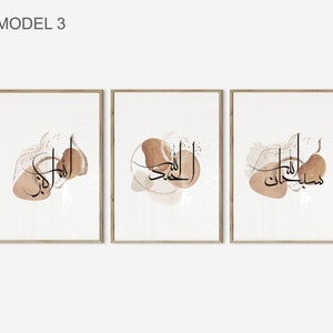 May include: Set of three framed prints with Arabic calligraphy in black on a white background. Each print features a different phrase in Arabic script with abstract brown watercolor shapes.
