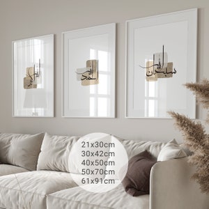 May include: Three white framed prints with Arabic calligraphy in black and gold on a white background. The prints are hanging on a white wall above a white couch with brown throw pillows. The text on the prints reads "Allah", "Alhamdulillah", and "Masha'Allah".