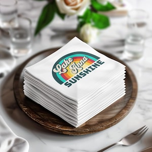 Stack of white napkins with "Lake Anna Sunshine" text and retro rainbow.