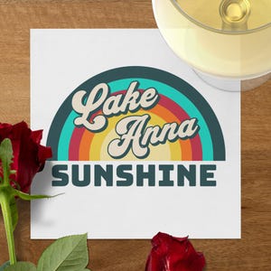 Lake Anna Sunshine text with rainbow graphic on paper, rose, and wine glass.