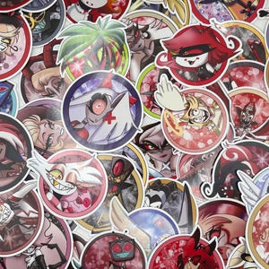 Puede incluir: Una colección de pegatinas circulares y coloridas con varios personajes de dibujos animados con contornos llamativos y colores vibrantes. Las pegatinas tienen una variedad de diseños, incluyendo personajes con esquemas de color rojo, blanco y negro, y algunos con temática demoníaca.
