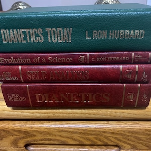 May include: A stack of four books with red and green covers. The books are titled "Dianetics Today", "Evolution of a Science", "Self Analysis", and "Dianetics". All books are by L. Ron Hubbard.
