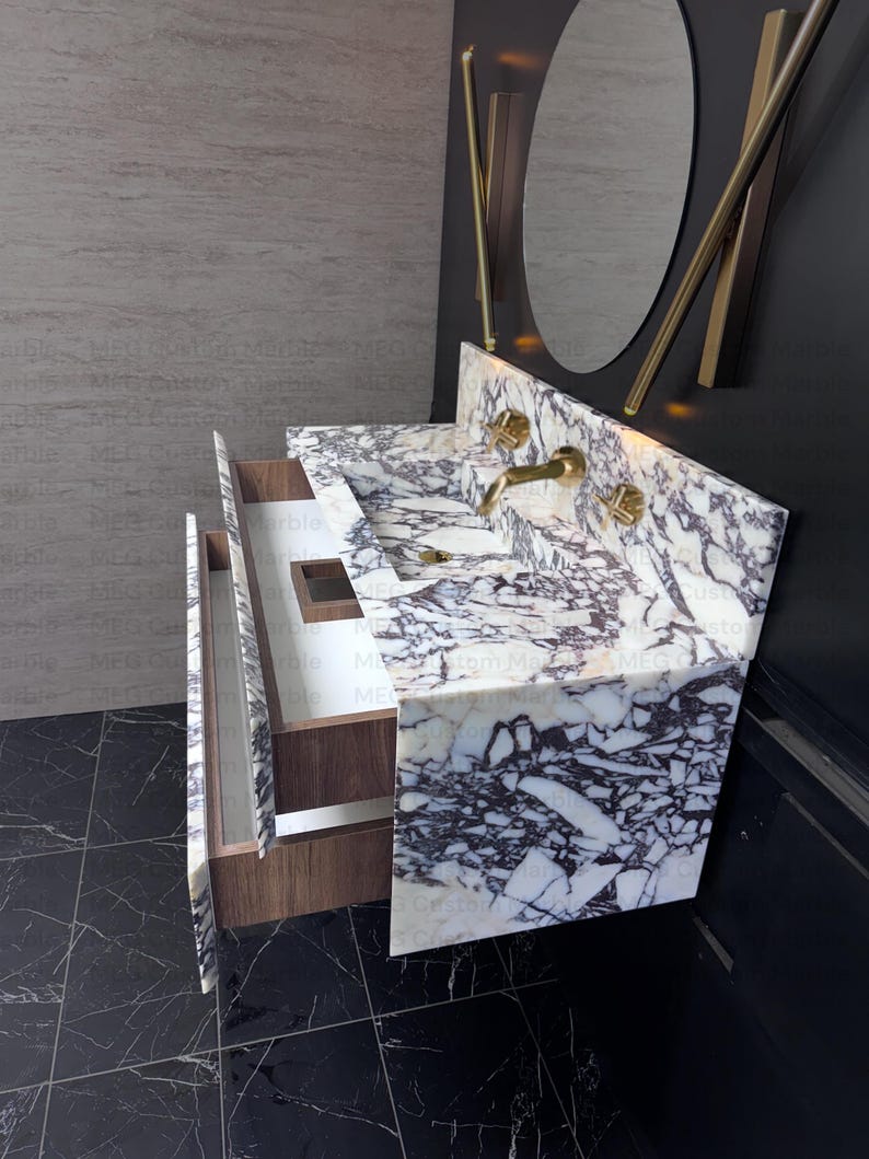 A white and purple marble bathroom vanity with two drawers. The vanity has a single sink and gold faucets. The vanity is mounted on a black tiled floor.