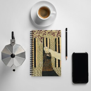 May include: A spiral bound notebook with a colorful illustration of a woman with long white hair standing in a doorway. The illustration is in a vintage style with a yellow, brown, and black color scheme.