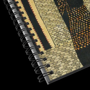 May include: Close-up of the binding of a spiral bound notebook with a black and white geometric pattern on the cover. The pattern features a brick wall and a stylized figure with a geometric design.