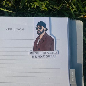 May include: A sticker featuring a cartoon illustration of a man wearing sunglasses and a brown jacket. The sticker has the text "NADIE SABE LO QUE VA A PASAR EN EL PRÓXIMO CAPÍTULO" in Spanish.