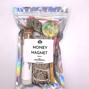 May include: A clear plastic bag containing a money magnet ritual kit. The kit includes sage, palo santo, pyrite, and a spiritual bath intention candle. The bag has the text "MONEY MAGNET RITUAL KIT" printed on it.