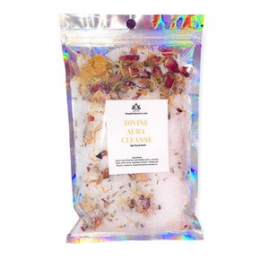 Peut inclure: Un sac en plastique transparent rempli de sels de bain blancs, de fleurs séchées et d'herbes. Le sac porte une étiquette sur laquelle est inscrit "Divine Aura Cleanse Spiritual Bath".