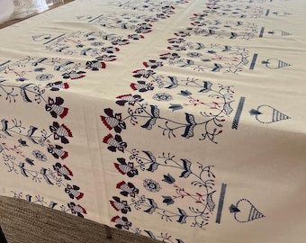 May include: A rectangular off-white tablecloth featuring a repeating pattern of dark blue and red floral motifs. The design includes stylized flowers, vines, and heart-shaped elements arranged in vertical columns across the fabric surface.