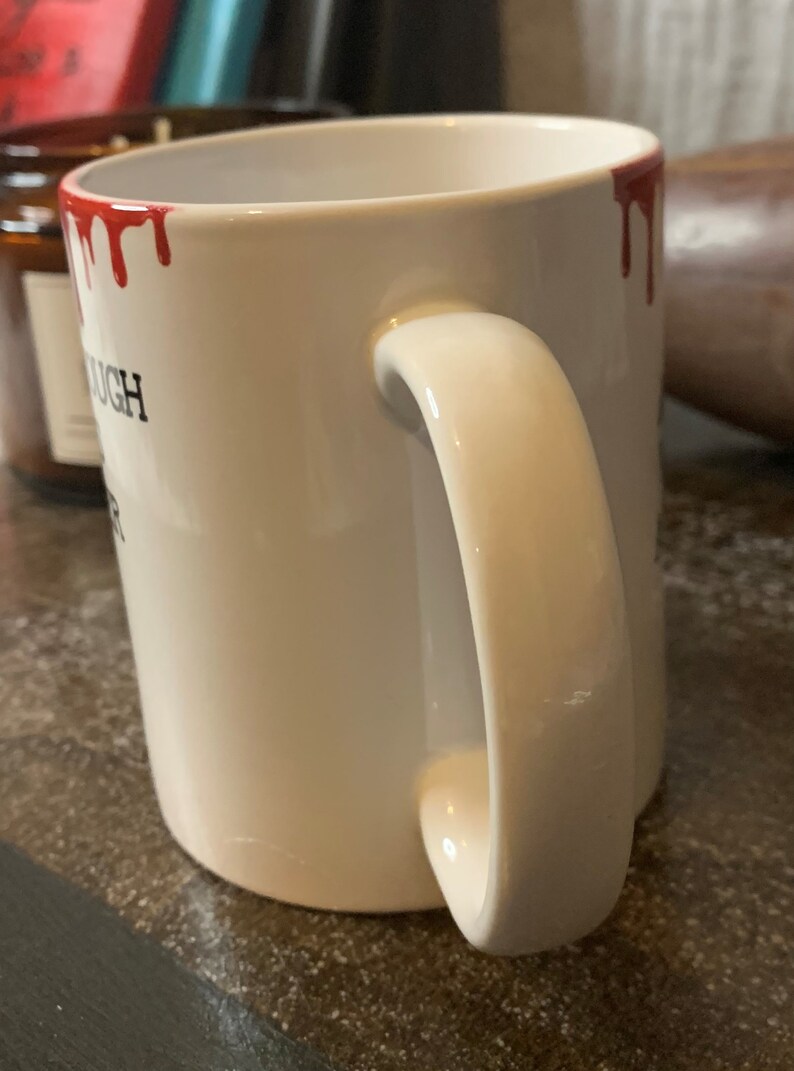May include: White ceramic mug with a red dripping paint design around the rim. The mug has a black inscription that reads "You're Enough".