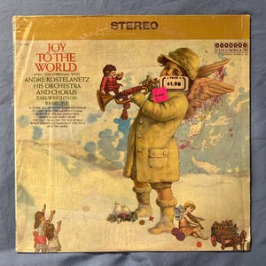 Puede incluir: Una portada de álbum de vinilo vintage con un ángel querubín tocando la trompeta con un paisaje invernal nevado de fondo. El título del álbum es "Joy to the World" con el artista "Andre Kostelanetz" y el texto "Música para Navidad con su orquesta y coro, Earl Wrightson, Barítono".