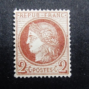 May include: A brown and white French postage stamp with the text "REPUB FRAN C" and "2 C POSTES C 2". The stamp features a profile of a woman with a wreath on her head.