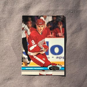 May include: A red, white, and blue hockey card featuring Sergei Fedorov, a professional ice hockey player. The card is from the 1993-94 Topps Stadium Club series.