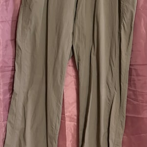 May include: A pair of khaki-coloured trousers with a button fastening and two front pockets.