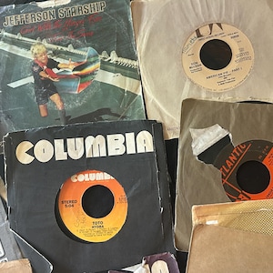 May include: A collection of vintage vinyl records, including Jefferson Starship, Don McLean, Toto, and a record with the text "Atlantic" on the label. The records are in various colors, including black, brown, and white.