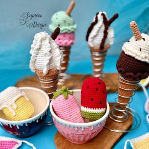 Puede incluir: Conos de helado y otras golosinas de ganchillo en varios colores. La imagen incluye varios conos de helado con bolas de diferentes colores, una fresa y una sandía. El texto "Seynooo Design" está en la esquina superior izquierda.