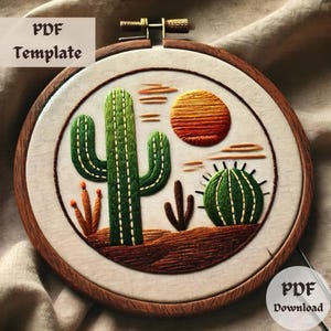 Op de afbeelding: Borduurwerk in een ronde hoepel met een woestijnscène met een grote groene cactus, een kleinere groene cactus, een ronde groene cactus en een ondergaande zon in oranje, gele en rode tinten.