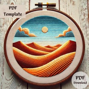 May include: A detailed embroidery hoop featuring a desert landscape with orange dunes, a yellow sun, and blue sky. The text "PDF Template" and "PDF Download" are visible. The embroidery is set in a wooden hoop.