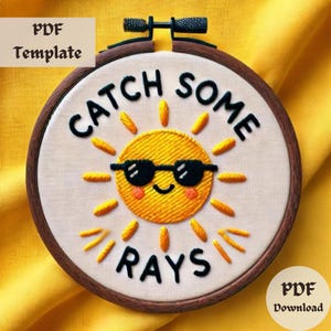 Peut inclure: Art de broderie en forme de cercle avec un soleil jaune portant des lunettes de soleil et le texte "Catch Some Rays" en noir.