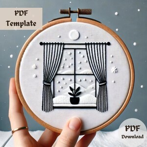 May include: Embroidered hoop art featuring a winter scene. The design includes a window with curtains, a potted plant, and falling snow. The text "PDF Template" and "PDF Download" are visible. The hoop is made of wood.