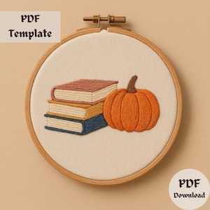 Peut inclure: Modèle de broderie pour une pile de trois livres et une citrouille. Les livres sont bruns, jaunes et bleus. La citrouille est orange. Le motif est sur un fond beige.