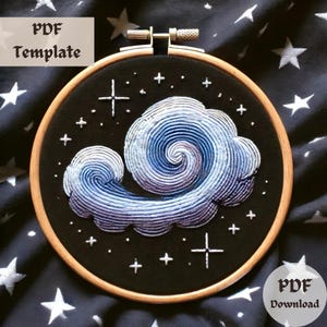 May include: Embroidery pattern for a swirling cloud with stars on a black background. The pattern is in a hoop and ready to be stitched.