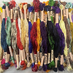 Puede incluir: Una colecci&oacute;n de carretes de hilo de bordar de colores con la palabra "Oasis" impresa en las etiquetas. Los carretes est&aacute;n dispuestos en fila y est&aacute;n listos para proyectos de artesan&iacute;a.