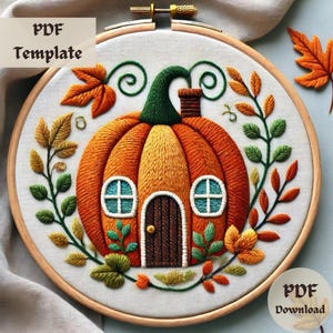 May include: Embroidered pumpkin house with a green stem and brown door, surrounded by leaves in shades of green, orange, and yellow. The embroidery is on a white fabric background and is framed in a wooden hoop.