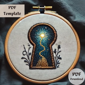 May include: Embroidered keyhole design with a starry night sky, a winding path, and a golden mountain inside. The embroidery is framed in a wooden hoop.