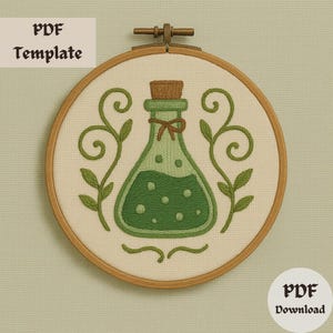 May include: Embroidered design in a wooden hoop featuring a green potion bottle with a cork stopper and a brown ribbon. The design includes green leaves and the text "PDF Template" and "PDF Download".