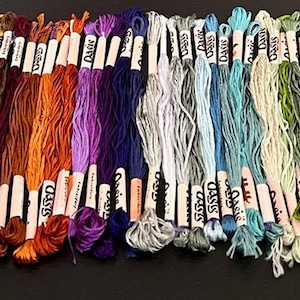 Puede incluir: Una colecci&oacute;n de 30 ovillos de hilo de bordar en varios colores, incluyendo rojo, naranja, amarillo, verde, azul, morado, rosa, marr&oacute;n y blanco. Cada ovillo est&aacute; etiquetado con "Classic" y tiene un fondo blanco con texto negro.