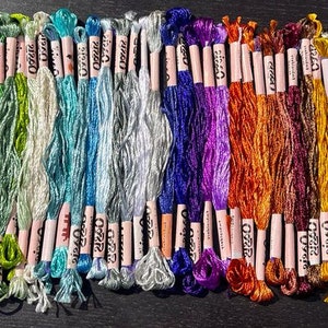 Puede incluir: Una colecci&oacute;n de 40 carretes de hilo de bordar en varios colores, incluyendo rosa, naranja, amarillo, verde, azul, morado, rojo, marr&oacute;n y plateado. Cada carrete est&aacute; etiquetado con "DMC" y tiene un n&uacute;mero impreso.
